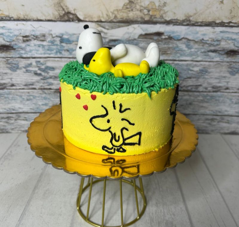 Tarta de cumpleaños temática de Woodstock y Snoopy con figuras de fondant.