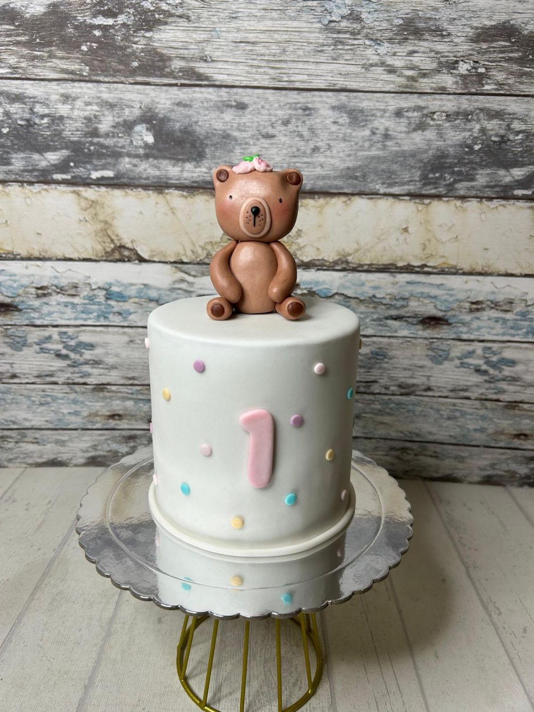 Tarta fondant personalizada de un año con osa artesanal y decoración minimalista en tonos pastel.