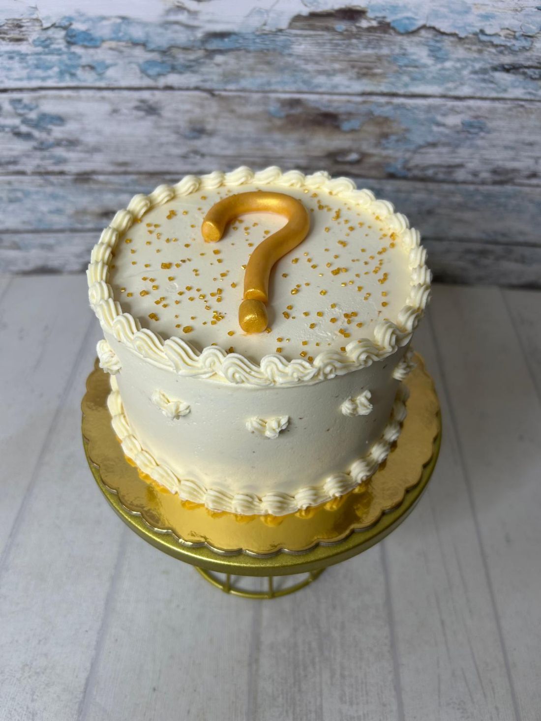 Tarta fondant de crema para revelación de género decorado con signo de interrogación en oro
