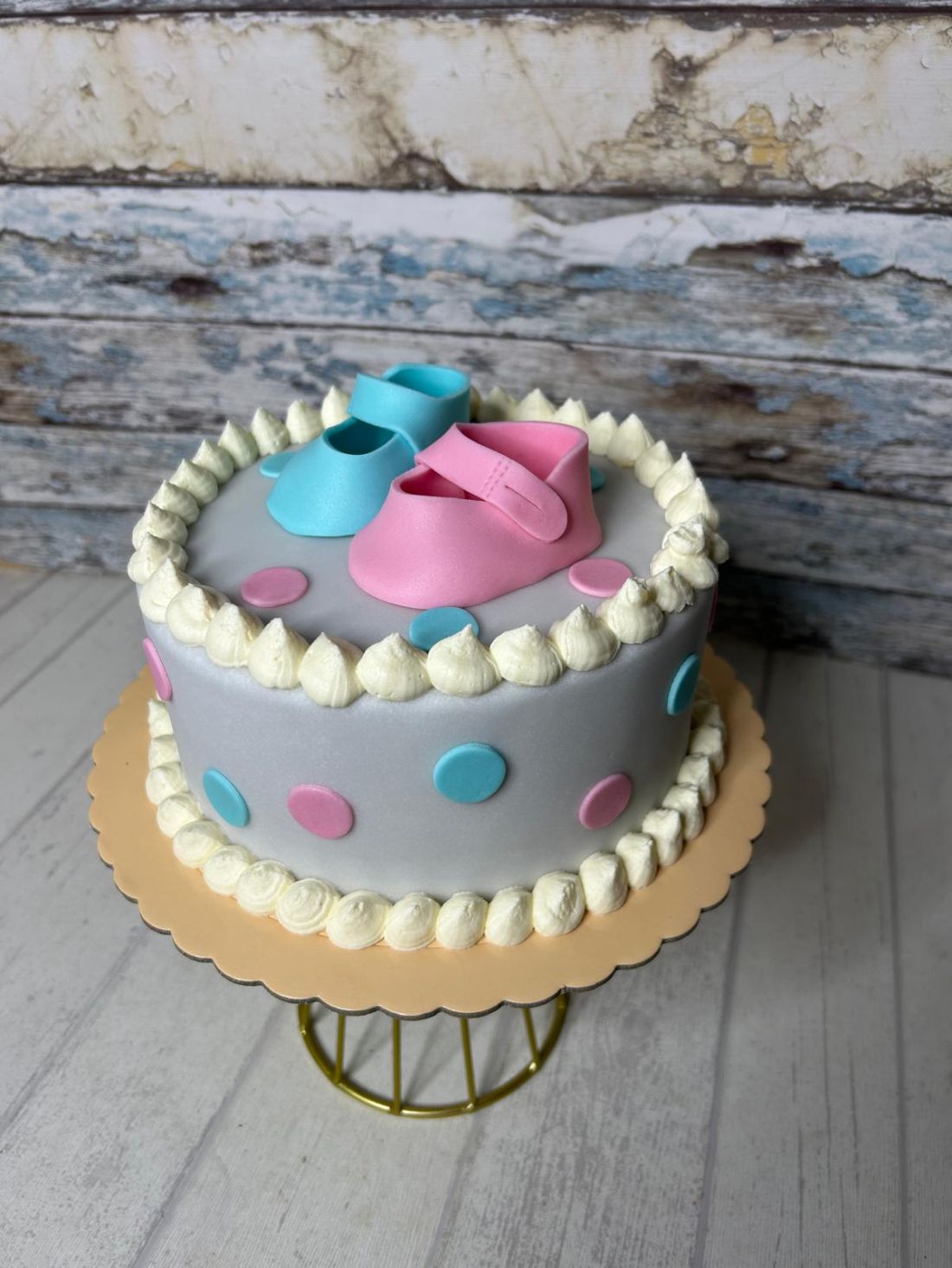 Tarta fondant para fiesta de revelación de género decorado con zapatitos de fondant rosa y azul sobre base gris
