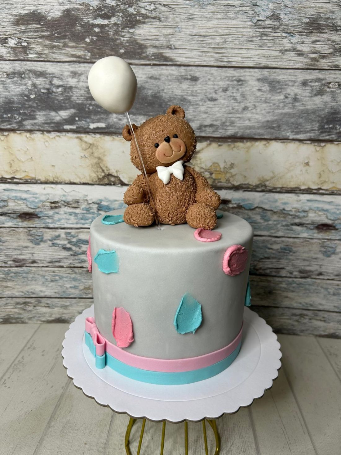 Tarta fondant gris con oso de peluche marrón, globo blanco y detalles rosa y azul para fiesta infatil.