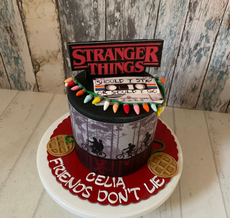 Tarta fondant de cumpleaños personalizado de Stranger Things para Celia con cassette y siluetas de bicicletas.