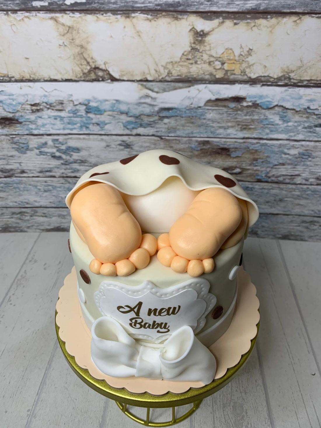 Tarta personalizada para baby shower decorada con figura de pies de bebé, manta de lunares y lazo de azúcar