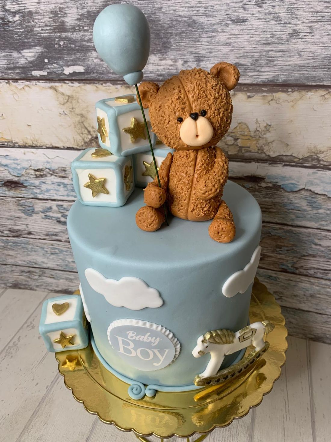 Tarta fondant con peluche agarrando globo con cajas alrededor y nubes